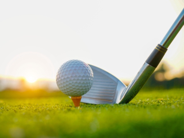 Golf clubs and golf balls on a green lawn in a beautiful golf course with morning sunshine. Close up of golf equipment on green grass.