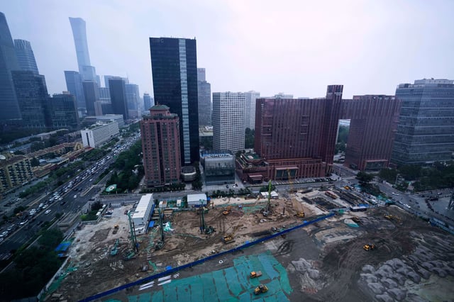 Earth movers transport soil at a construction site in Beijing, China, Friday, July 11, 2025. (AP Photo/Mahesh Kumar A.)