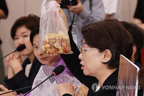 Rep. Lee Dal-hee of the main opposition People Power Party holds up a plastic bag of food waste during a parliamentary confirmation hearing on Gender Equality Minister nominee Kang Sun-woo on July 14, 2025, as she addressed allegations that Kang abused her authority by ordering her aides to do her household chores, such as disposing of food waste at her home. (Yonhap)