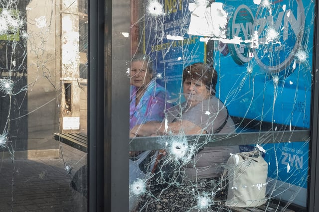 Des femmes sont assises à un arrêt de bus endommagé lors des frappes de drones et de missiles russes, au milieu de l'attaque de la Russie contre l'Ukraine, à Kyiv, Ukraine, le 10 juillet 2025.