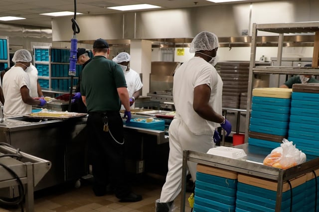Workers, including some detainees, prepare trays containing meals to be served to detainees during a media tour of the U.S. Immigration and Customs Enforcement detention center,  in Tacoma, Wash., on Dec. 16, 2019.