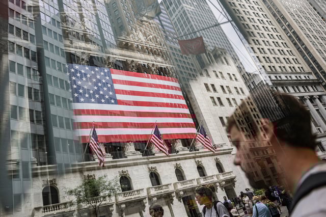 People walk past the New York Stock Exchange (NYSE) in New York City, U.S., July 11, 2025. Picture taken through glass. REUTERS/Jeenah Moon