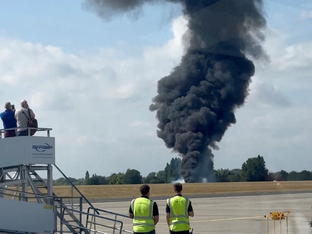 A plume of black smoke rises from an area near the runway after a small plane crash, as seen from inside a building at London Southend Airport, in Southend, Britain, July 13, 2025, in this screen grab obtained from a social media video. @agussromagnoli via X/via REUTERS  THIS IMAGE HAS BEEN SUPPLIED BY A THIRD PARTY. MANDATORY CREDIT.   VERIFICATION - Airport runway outline and trees that matched file and satellite imagery. Coordinates included in original file metadata - Date was verified by original file metadata