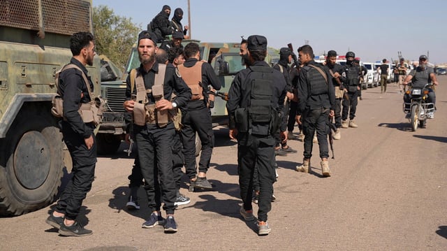 Eine Gruppe Männer mit Waffen steht auf einer Straße am Rande der Region Suwaida in Syrien