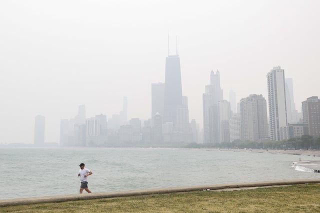 A jogger runs along the shoreline of Lake Michigan with heavy smoke from the Canadian wildfires in the background, on June 27, 2023, in Chicago, Illinois.