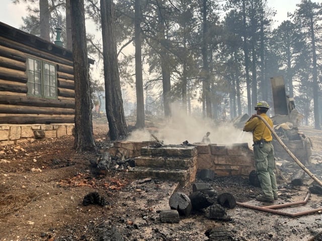 A firefighter stands near smoldering debris amid the charred remains of a burned structure near the Grand Canyon Lodge in Arizona, U.S.  July 13, 2025.    National Park Service/Handout via REUTERS    THIS IMAGE HAS BEEN SUPPLIED BY A THIRD PARTY. MANDATORY CREDIT.