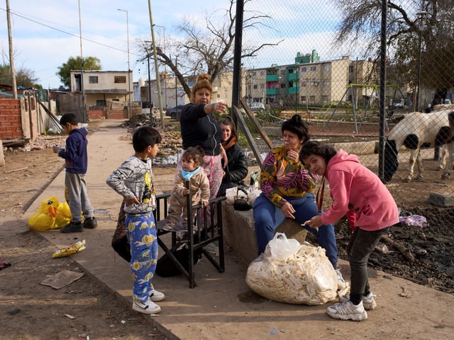 Neighbors eat bread donated by a bakery in the Garrote neighborhood of Buenos Aires, Argentina, Tuesday, June 3, 2025. (AP Photo/Rodrigo Abd)  VILLA GARROTE - VILLA EL GARROTE - BARRIO EL GARROTE -  SAN FERNANDO -  POBREZA