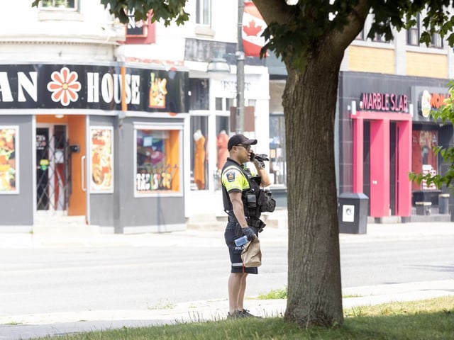  A member of the London police foot patrol talks to a man loitering outside First Baptist Church on Richmond Row in London, Ontario on Monday July 14, 2025. (Derek Ruttan/The London Free Press)