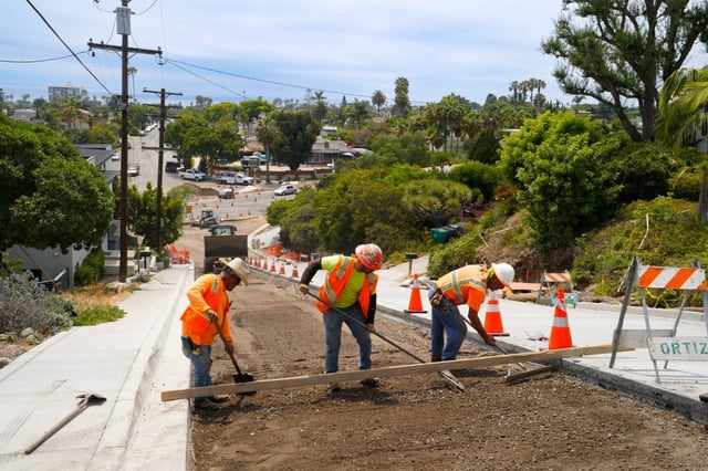 Construction workers level a large section of underlayment soil along Loring Street. (Nelvin C. Cepeda / The San Diego Union-Tribune)