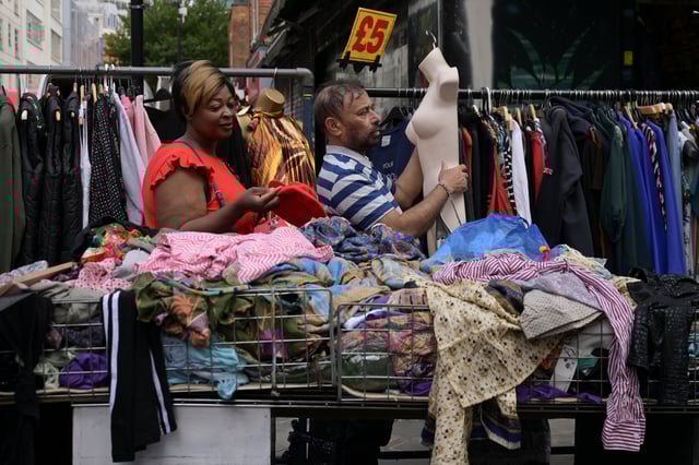 A stallholder moves a mannequin while a woman shops at the Petticoat Lane Market in Tower Hamlets in London, Britain, June 1, 2025.  REUTERS/Jaimi Joy/File Photo
