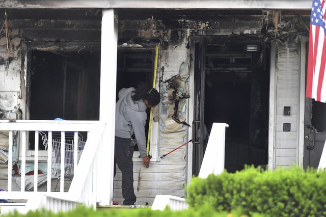An investigator takes measurements Monday, July 14, 2025, near an entrance to the Gabriel House assisted living facility following a fire that started late Sunday in Fall River, Mass. (AP Photo/Steven Senne)