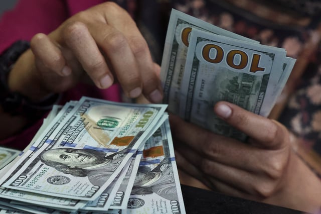 A teller counts U.S. dollar bank notes at a money changer in Jakarta, Indonesia, April 9, 2025. Picture taken through glass. REUTERS/Willy Kurniawan/ File Photo
