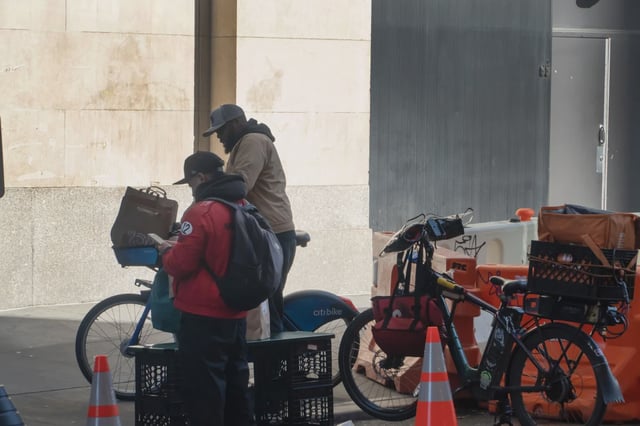 Two men wait for and repack orders prior to delivering them by bicycle.