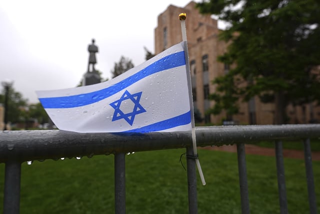 FILE - The flag of Israel tops a makeshift memorial for victims of an attack outside of the Boulder County, Colo., courthouse as a light rain falls, June 3, 2025, in Boulder, Colo. (AP Photo/David Zalubowski, File)