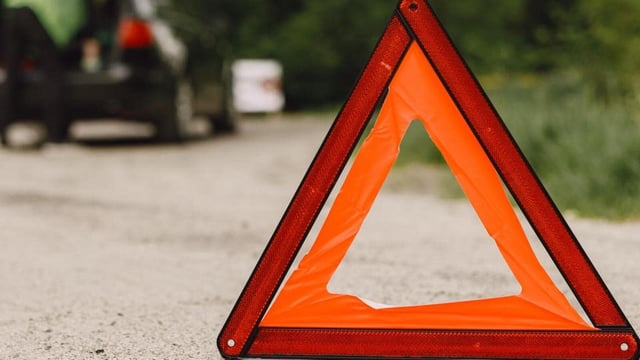Driver putting warning triangle on asphalt road. Emergency stop concept.