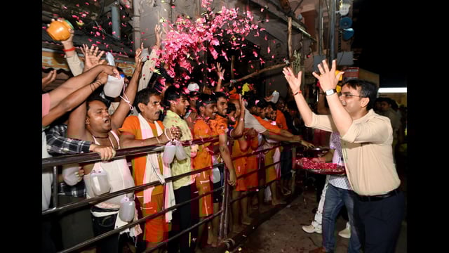 District magistrate Satyendra Kumar showers flower petals on the devotees standing in queue to offer prayers at the Kashi Vishwanath temple on the first Monday of Sawan, in Varanasi on Monday. (Kashi Vishwanath Temple)