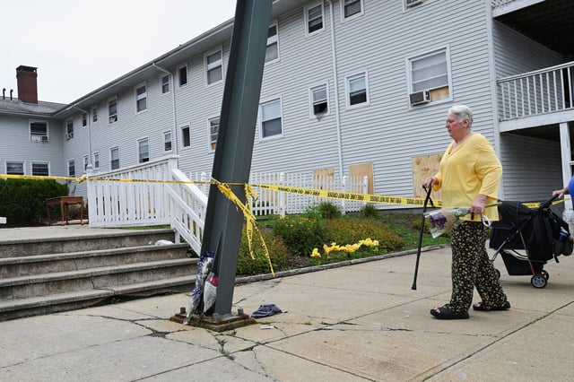 Kathleen Banuelos of Fall River brings a bouquet of flowers to the Gabriel House Assisted Living Facility after a deadly fire in Fall River, Massachusetts Monday.