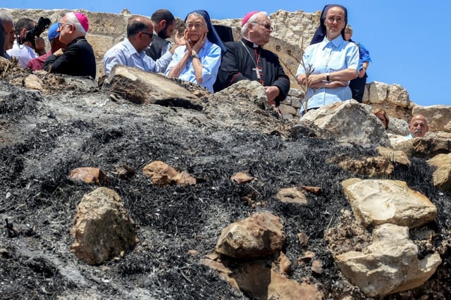 Des religieuses et des ecclésiastiques catholiques devant l'église Saint-Georges du Ve siècle dans le village chrétien palestinien de Taybeh, au nord-est de Ramallah en Cisjordanie occupée, le 14 juillet 2025
