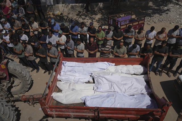 Mourners pray beside the bodies of Palestinians who were killed by an Israeli airstrike, during their funeral at Shifa Hospital in Gaza City Tuesday, July 15, 2025. (AP Photo/Jehad Alshrafi)