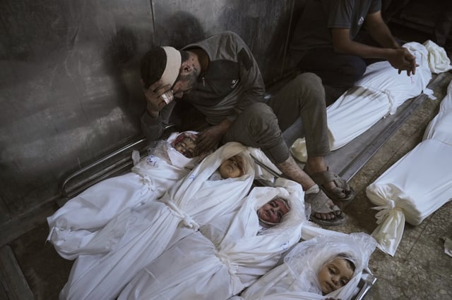 EDS NOTE: GRAPHIC CONTENT - Hossam Azzam mourns over the body of his son, Amir, and other relatives who were killed in an Israeli military airstrike on Gaza, at Shifa Hospital in Gaza City Tuesday, July 15, 2025. (AP Photo/Jehad Alshrafi)