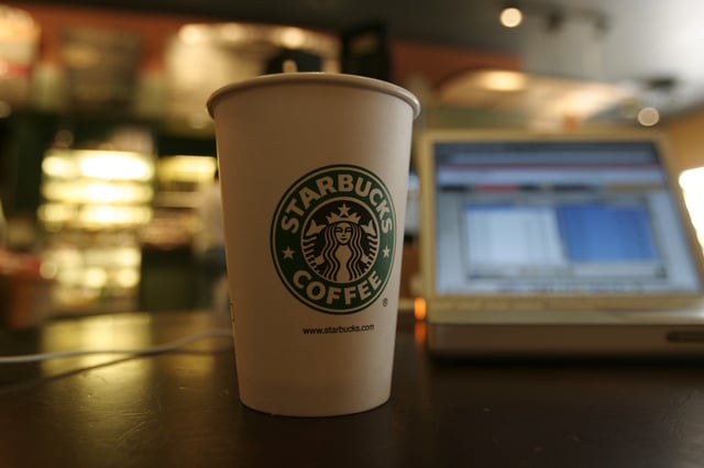 A Starbucks coffee cup sits next to a laptop in this undated archive stock photo.