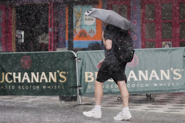 A pedestrian makes his way along a street during a rain shower Tuesday, July 15, 2025, in Orlando, Fla. (AP Photo/John Raoux)