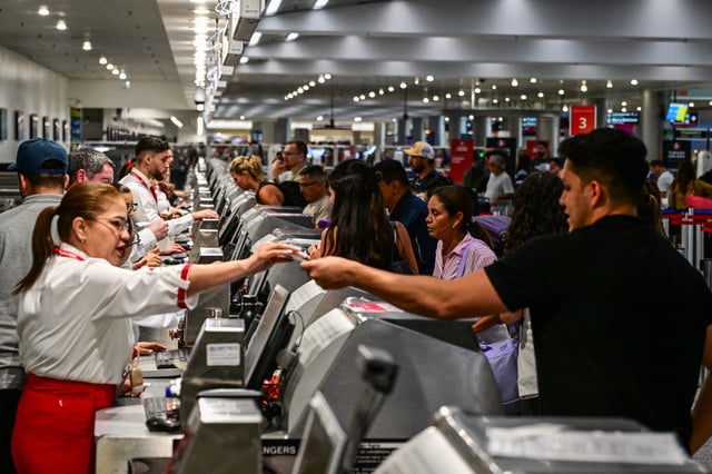 Travelers hand documents to airline staff at Miami International Airport during Memorial Day weekend on May 24, 2025 in Miami, Florida.