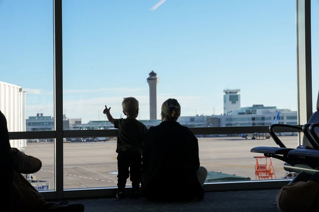 The air traffic control tower is seen from the gate as a woman and a child look out at the Denver International Airport terminal, in Denver, Colorado, U.S., May 15, 2025.  REUTERS/Megan Varner/File Photo