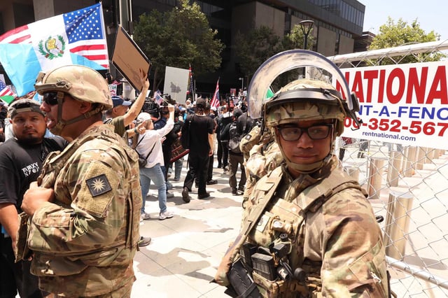 Members of the California National Guard stand by as thousands participate in the No Kings demonstration in downtown Los Angeles on June 14, 2025.