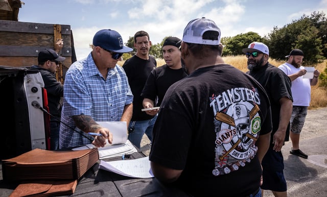 Mike Hughes, a business agent for Teamsters Local 315, left, disperses benefits checks to union members outside the Golden Bear Transfer Station in Richmond, Calif., on Tuesday, July 15, 2025. 