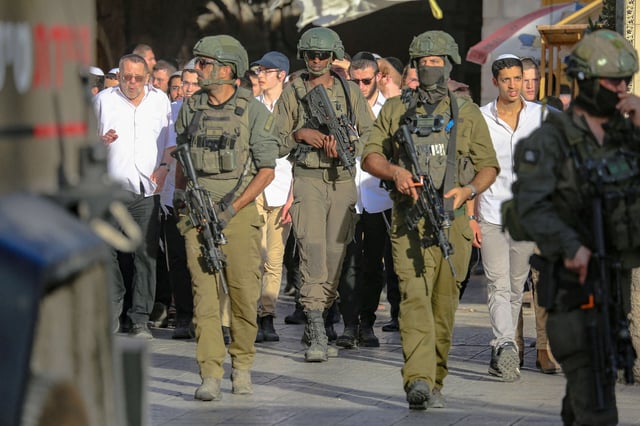 Israeli security forces stand guard as Israeli settlers tour the Palestinian side of the old city and market of Hebron in the occupied West Bank on July 12, 2025. Shops are forced to close, and Palestinians are prevented from reaching their homes due to the presence of settlers.