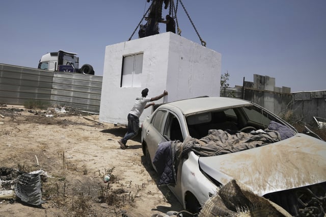 FILE - A resident guides a bomb shelter donated by the Israeli-Palestinian group Standing Together to the Bedouin community of Khirbet Al-Watan, southern Israel, where most villages are unrecognized by the state and use makeshift shelters to take cover from Iranian missiles, June 24, 2025. (AP Photo/Maya Alleruzzo, File)