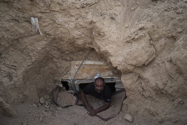 Ahmad Abu Ganima poses for a portrait in the window of the minibus buried in the earth, a makeshift bomb shelter his family uses in Khashem Zaneh, an unrecognized Bedouin village in the Negev Desert, southern Israel, Wednesday, July 2, 2025. (AP Photo/Maya Alleruzzo)