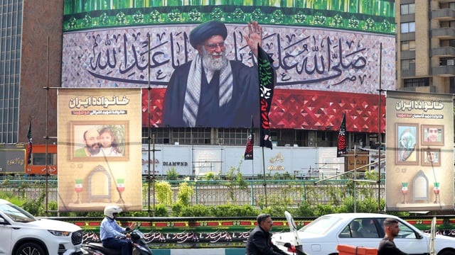 Motorists drive their vehicles past a billboard depicting Iran's Supreme Leader Ayatollah Ali Khamenei displayed in the centre of Tehran's Valiasr Square on July 13