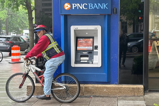 A cyclist stands near a branch of PNC Bank, a subsidiary of PNC Financial Services Group, in Washington, U.S. April 30, 2023.  REUTERS/Ashraf Fahim/File Photo