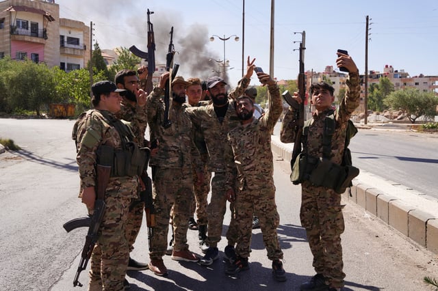 Des membres des forces de sécurité syriennes se tiennent ensemble et utilisent leurs téléphones mobiles après que les troupes syriennes sont entrées dans la ville majoritairement druze de Soueïda.