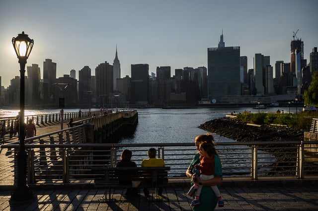 People walk before the United Nations headquarters and the city skyline of New York, in Queens on September 19, 2023.