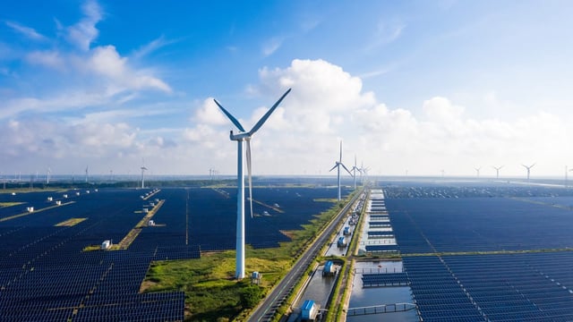 Image of windmills towering over solar farms.