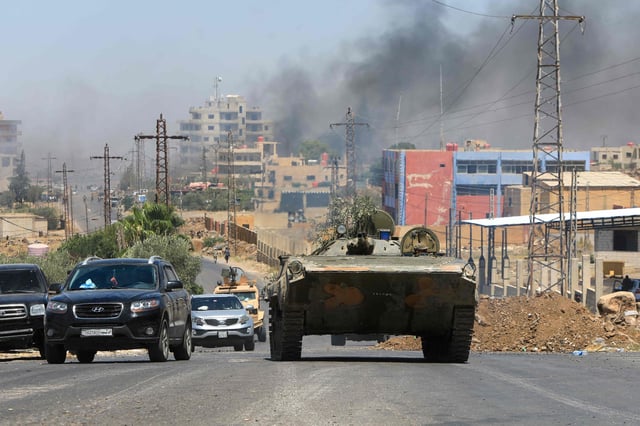 Miembros de las fuerzas de seguridad sirias recorren la ciudad de Sweida, de mayoría drusa, el 15 de julio de 2025, mientras se eleva una columna de humo tras los bombardeos israelíes tras los enfrentamientos entre tribus beduinas y combatientes drusos.