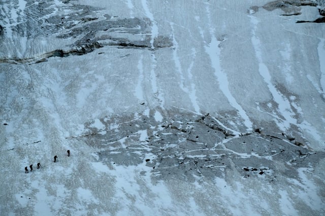 Des alpinistes marchent le long des crevasses du glacier de la Selle dans le massif des Écrins, tôt le matin, le 9 juillet 2025 à Saint-Christophe-en-Oisans, en Isère
