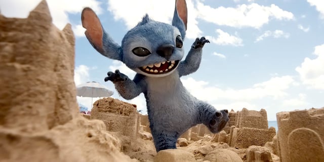 Stitch (Chris Sanders) crashes through sand castles like Godzilla in Lilo and Stitch (2025). 
