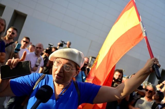 A woman holding a Spanish flag talks to media during a rally called by far-right groups in Torre Pacheco