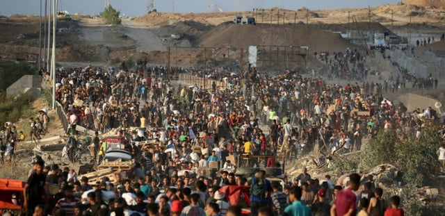 Des Palestiniens rassemblés à un point de distribution d'aide mis en place par la Fondation humanitaire de Gaza (GHF), près du camp de réfugiés de Nousseirat, dans le centre de la bande de Gaza, le 25 juin 2025