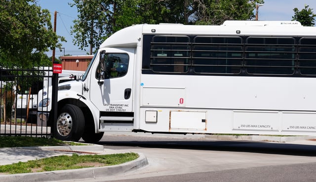 A bus with barred windows enters the secure parking lot of the Aurora GEO Detention Center on July 15, 2025.