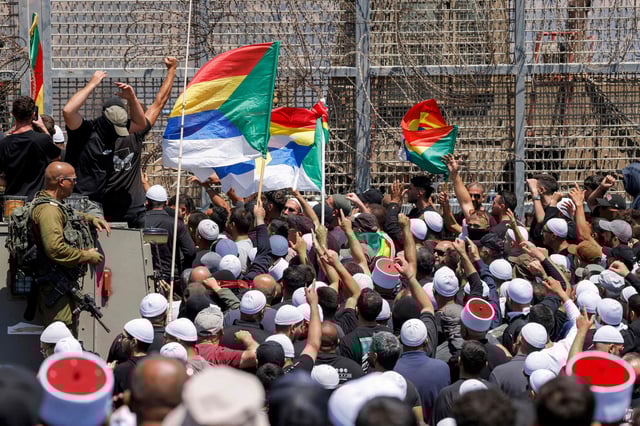 Miembros de la comunidad drusa se manifiestan ante las fuerzas israelíes junto a la valla de alambre de púas que separa los Altos del Golán, anexados por Israel, de Siria, cerca de Majdal Shams, el 16 de julio de 2025