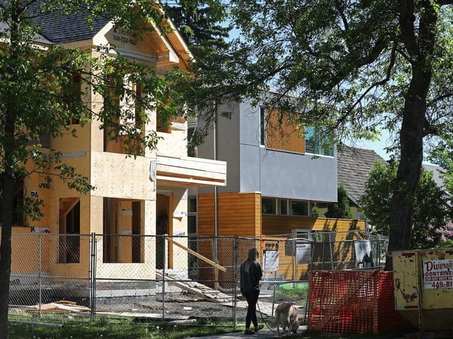 A pedestrian walks their dog past an under construction infill home in Edmonton's Parkallen neighbourhood, Friday June 11, 2021.
