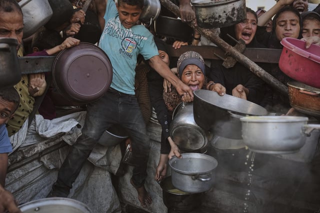 Los palestinos luchan por conseguir alimentos donados en una cocina comunitaria en la Ciudad de Gaza, en el norte de la Franja de Gaza, el lunes 14 de julio de 2025