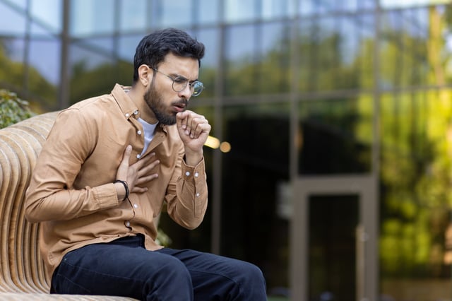 A stock photo of a man coughing.