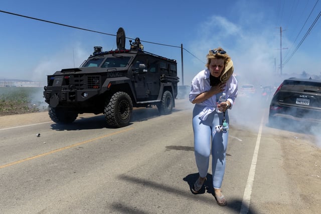 FILE: A protester flees as Customs and Border Protection agents fire chemical agents into the crowd during a raid at Glass House Farms in Camarillo, Calif., July 10, 2025.