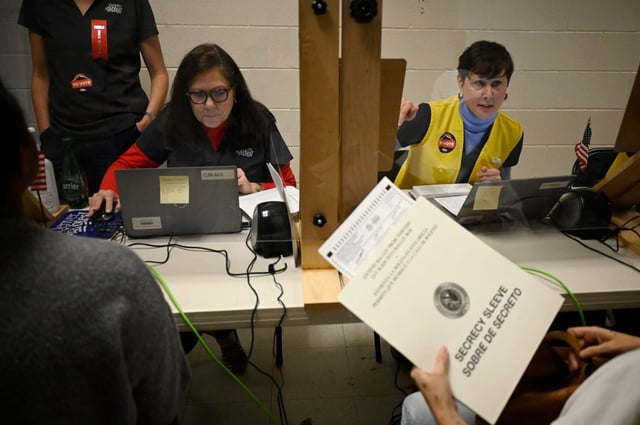 Election Judges Cindy Engel, left, and Zoe Krusic help voters with registration at a voter service and polling center in North High School in Denver on Tuesday, Nov. 8, 2022. (Photo by Hyoung Chang/The Denver Post)